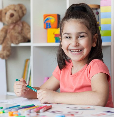 Bambina che ride in mentre disegna e colore in un'aula di Belt School Perugia